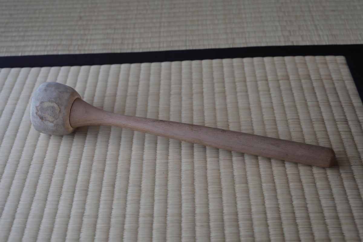 A wooden spoon rests on a woven mat.