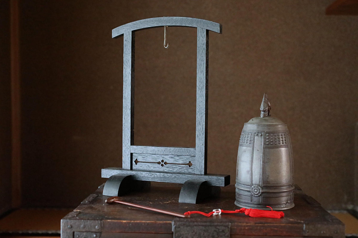 a wooden frame with a metal lid, a metal pitcher, and a red string, all placed on a wooden surface.