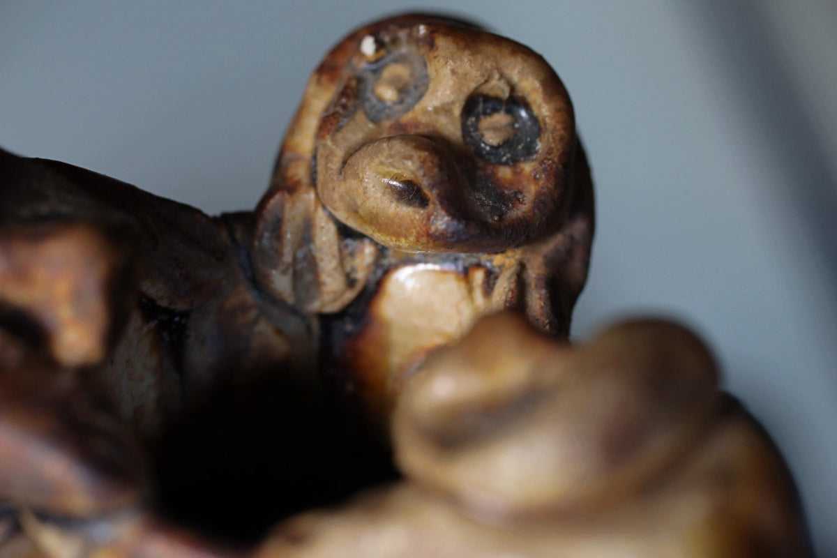 A close-up view of a brown, weathered sculpture with a face-like appearance, possibly made of wood or clay.