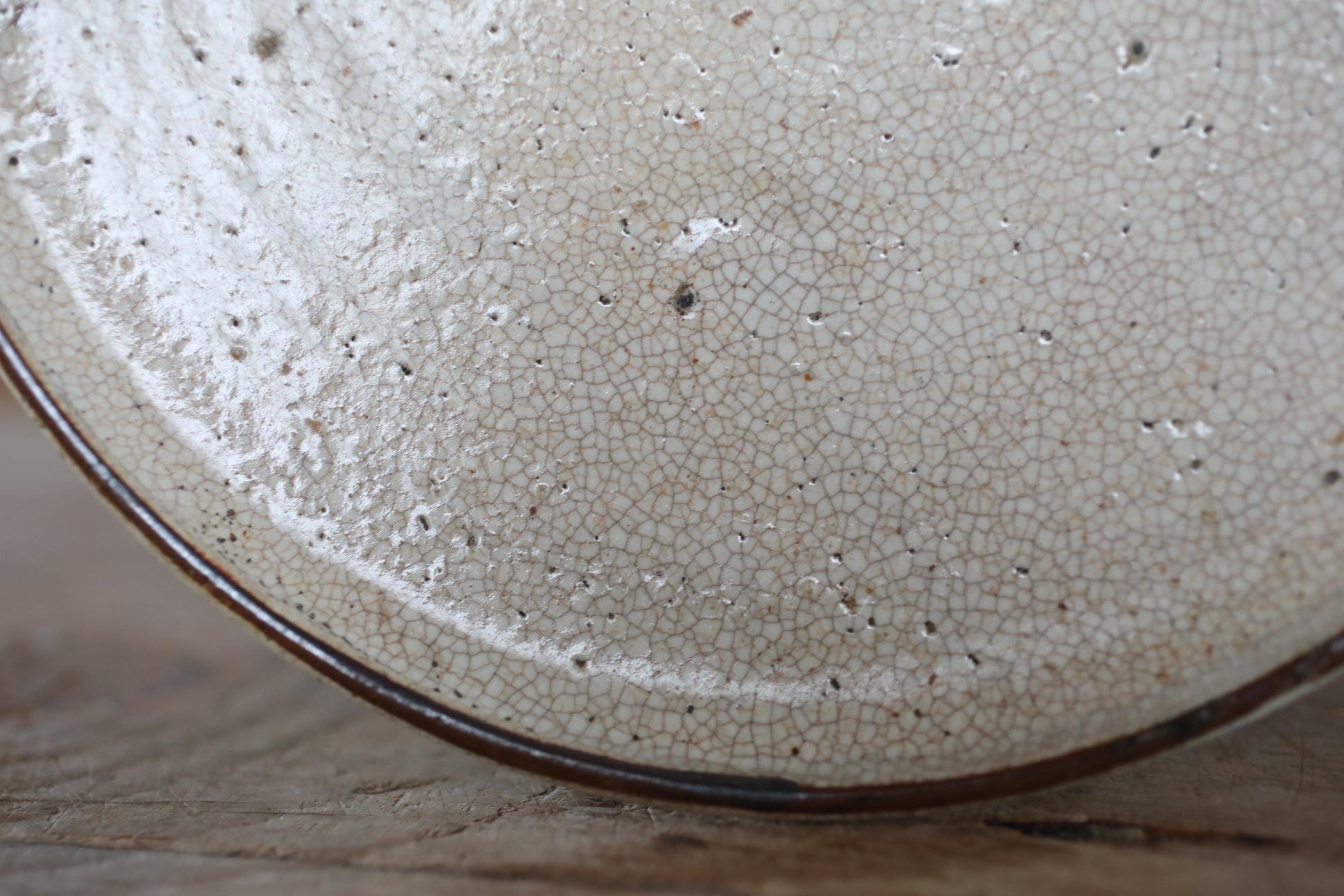 A close-up view of a white ceramic plate with a textured surface, featuring small holes and a dark border around the edge.