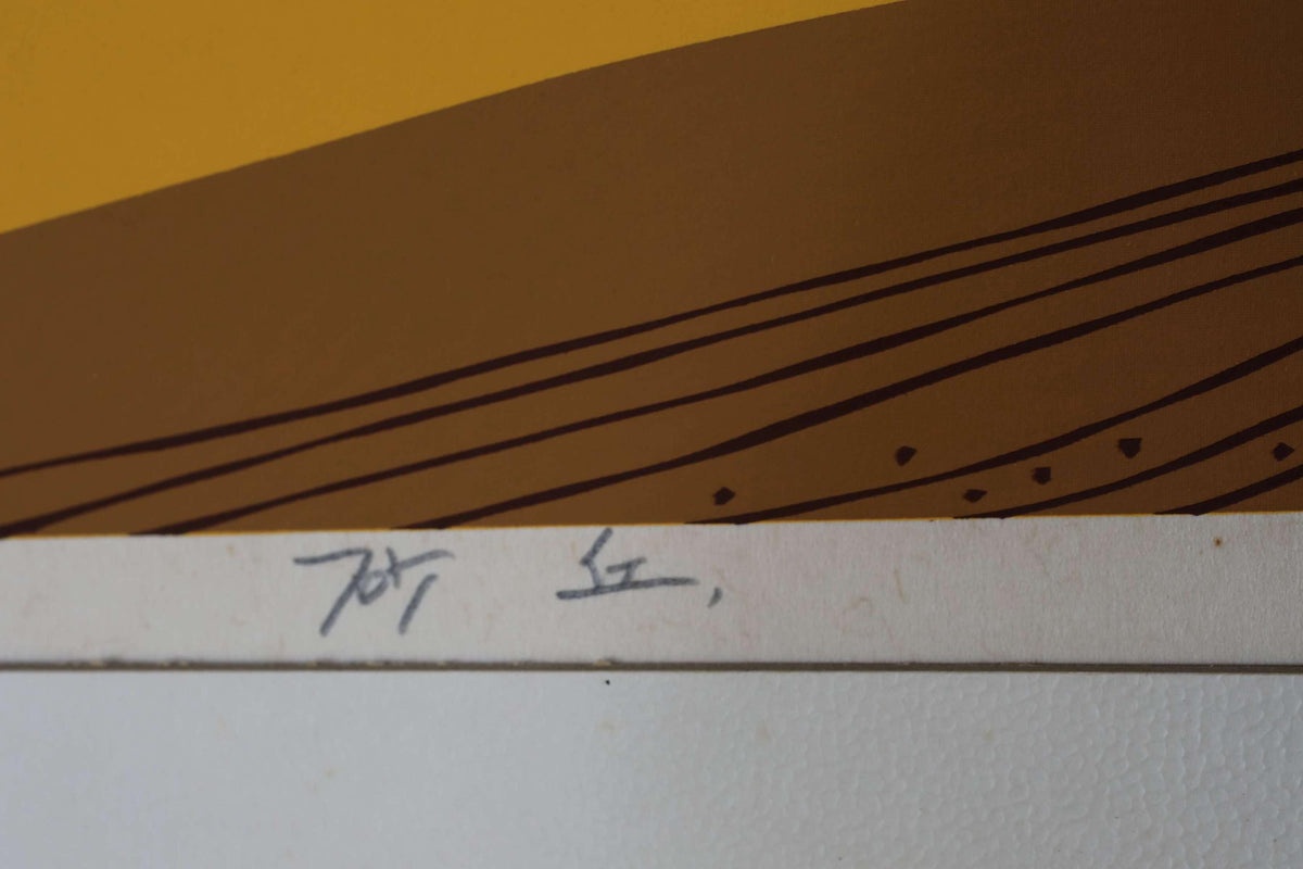 a close-up view of a white surface with a brown and yellow abstract design, including lines and dots. There is also some handwritten text on the surface.