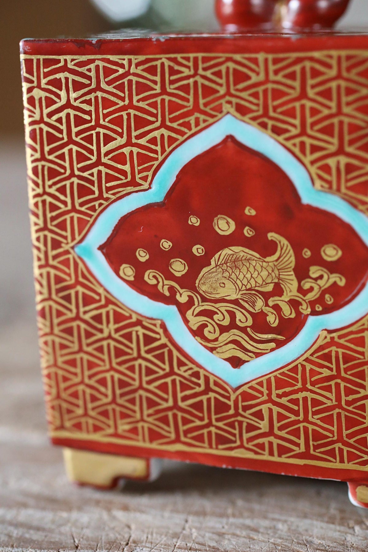 a red and gold decorative box with a fish design on the front.