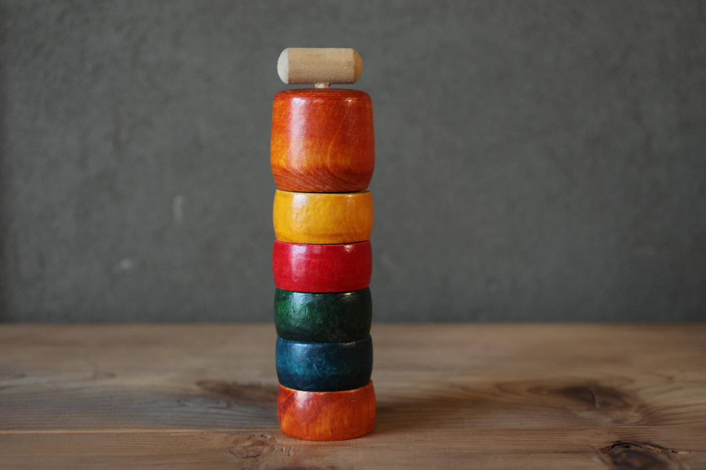 A stack of colorful wooden rings on a wooden surface.