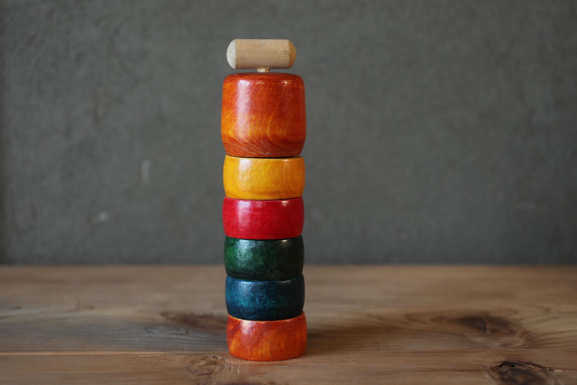 A stack of colorful wooden rings on a wooden surface.