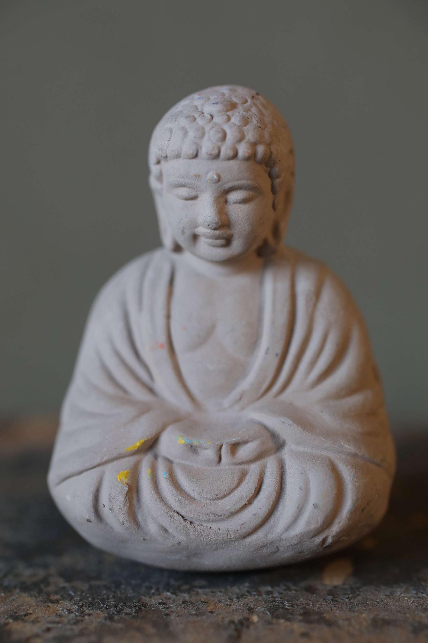 A small white Buddha statue sitting in a meditative pose, with a serene expression on its face.