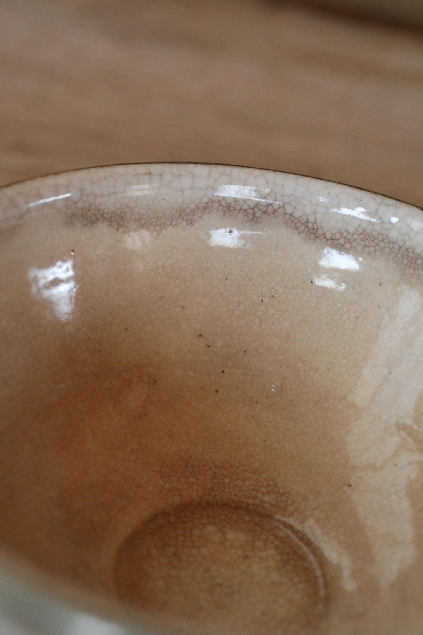 A close-up view of a ceramic bowl with a textured surface, featuring a few small spots and a small amount of liquid inside.