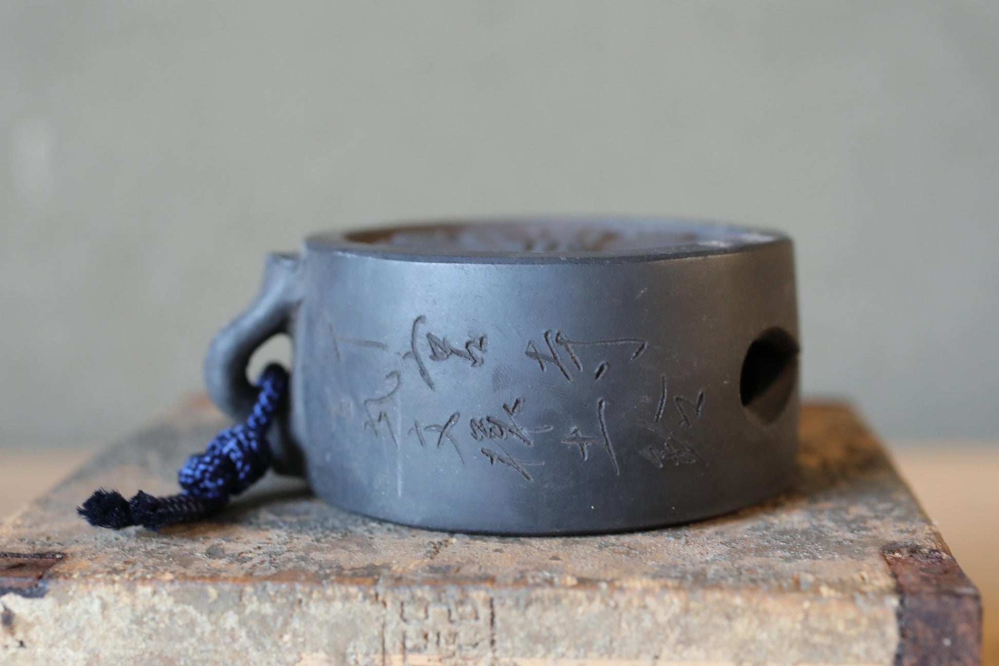 A black ceramic object with Chinese characters engraved on it, sitting on a wooden surface.