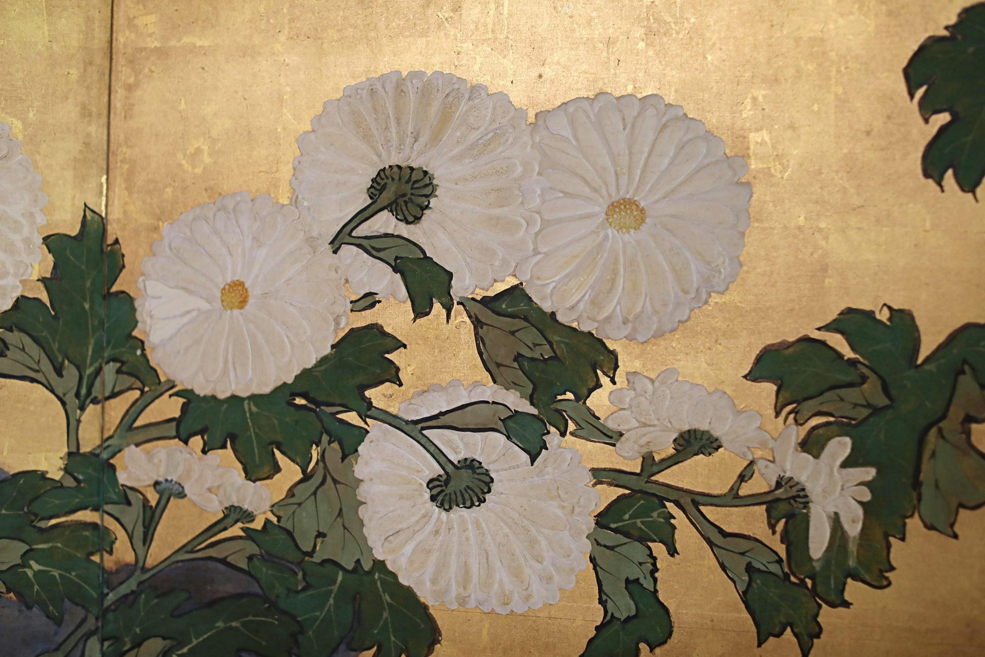 a close-up view of a painting featuring white flowers with green leaves.