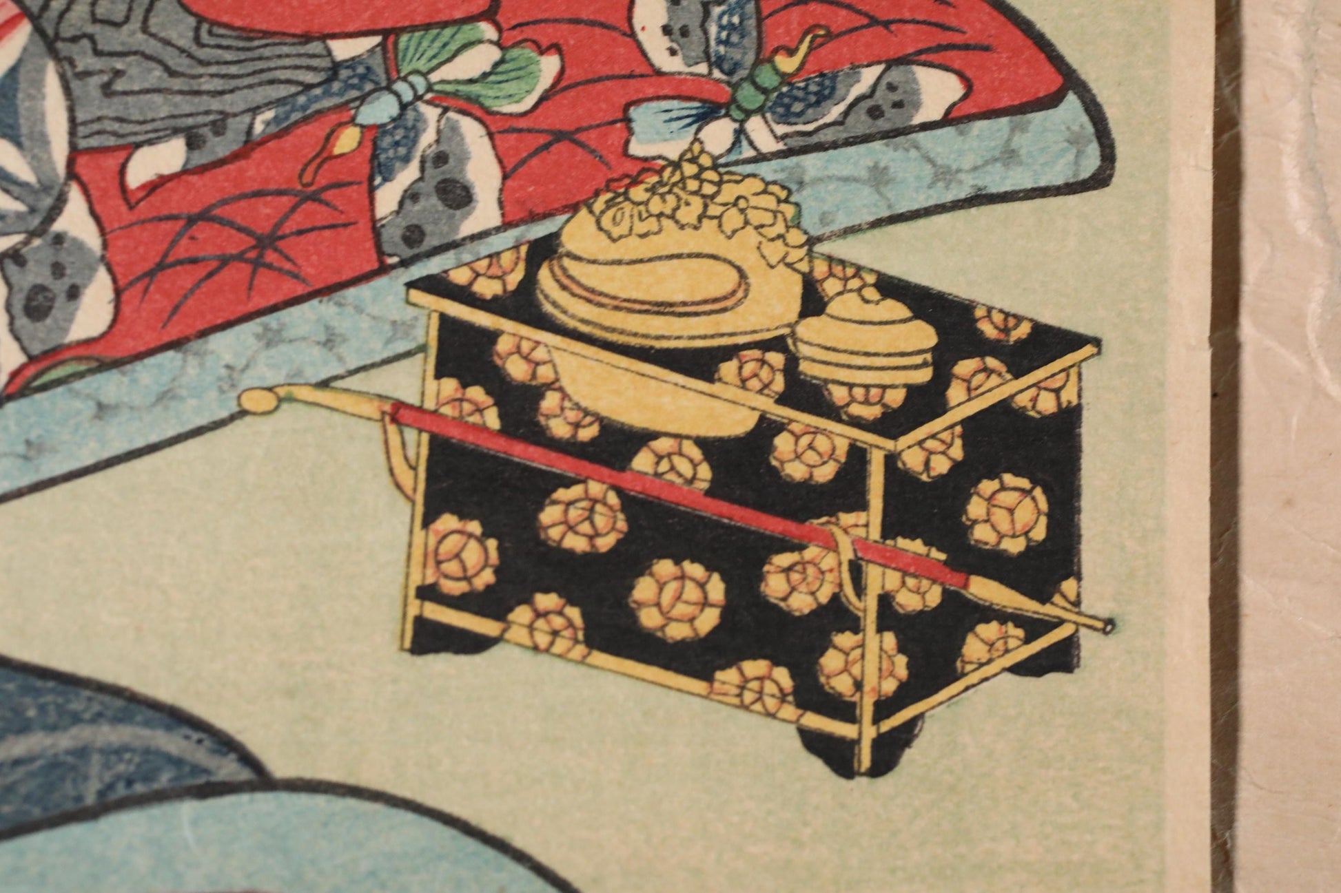 a decorative box with a red handle and a floral pattern on a black background.