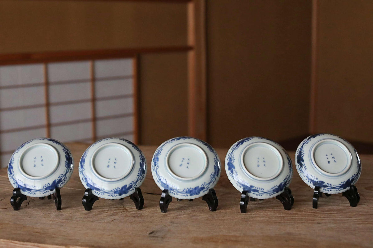 A row of five blue and white plates with intricate designs, displayed on a wooden surface.