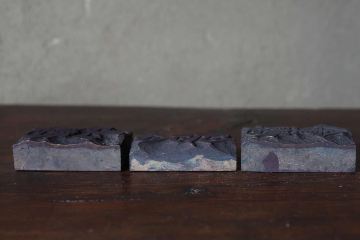 Three rectangular blocks of varying shades of blue are arranged on a wooden surface.