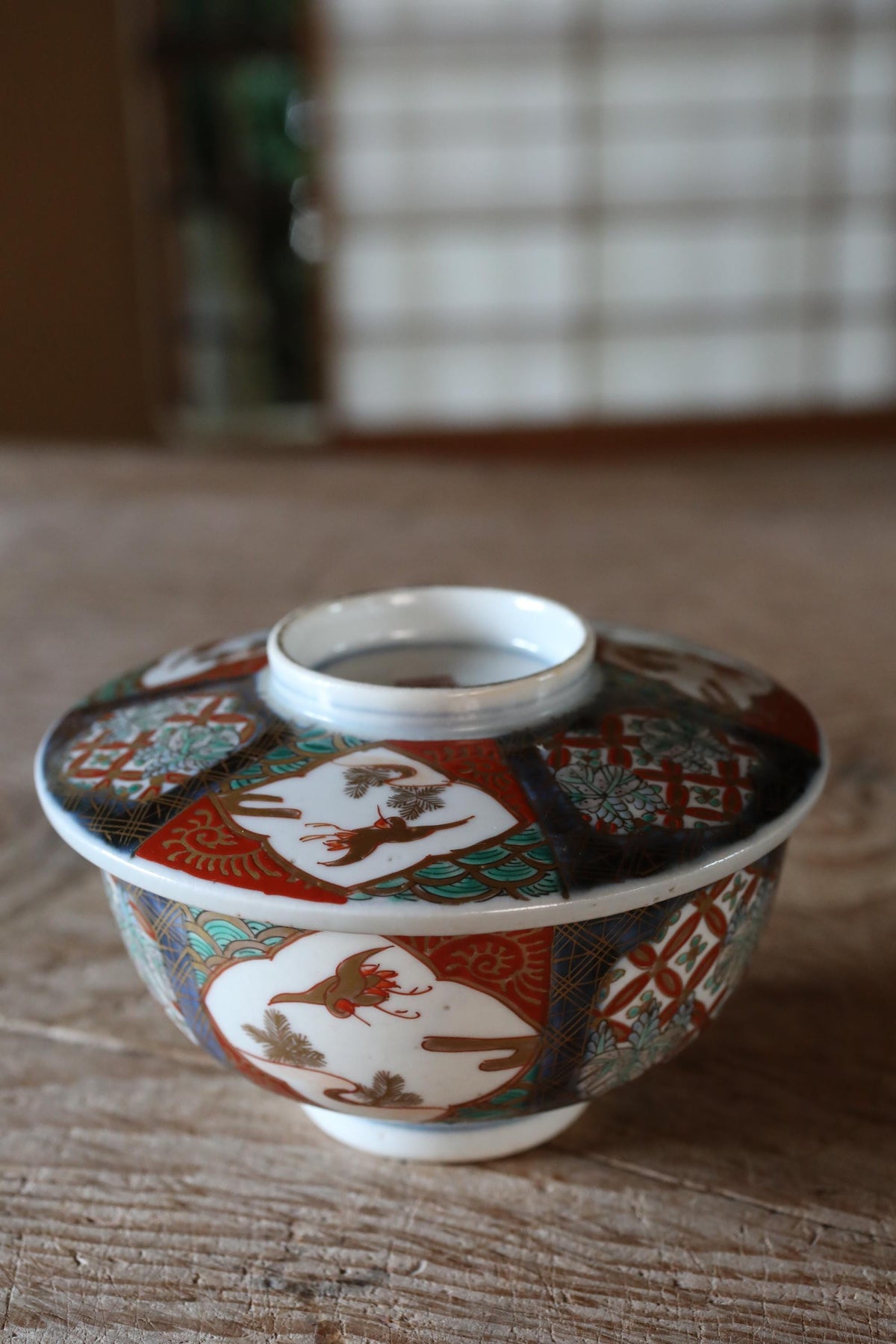 A colorful ceramic bowl with intricate patterns sits on a wooden surface.