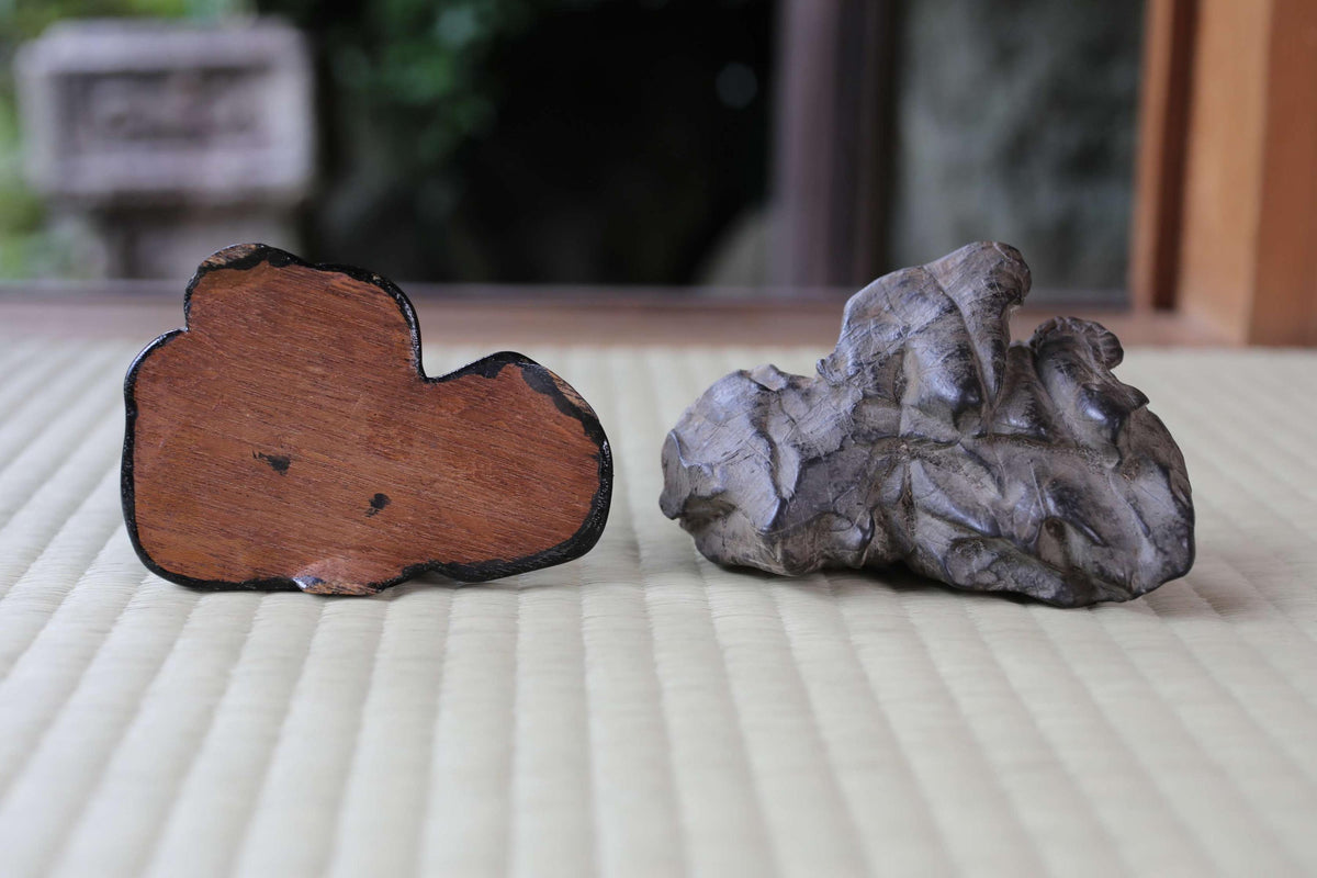 two distinct objects placed on a textured surface, one being a wooden object and the other a stone or rock.