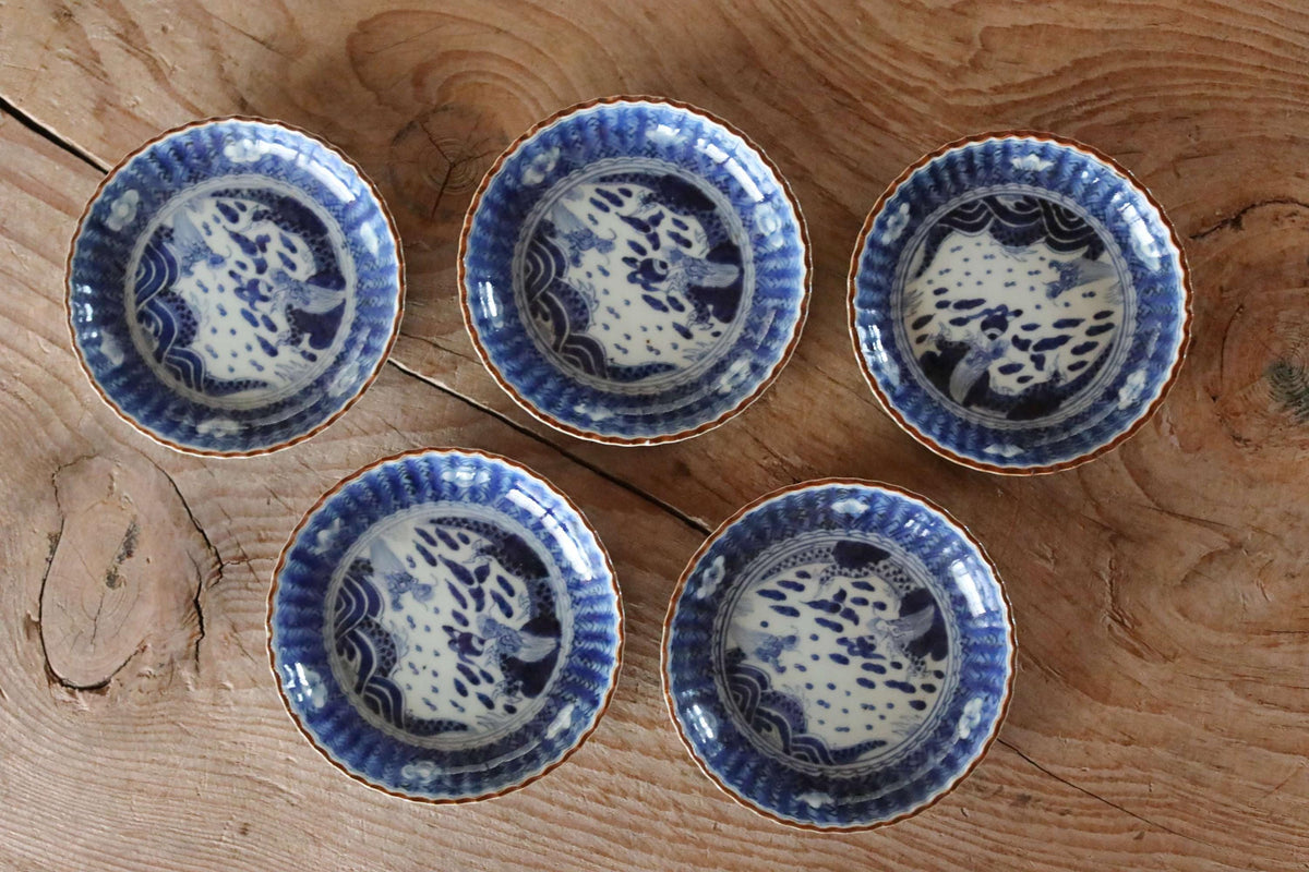 A group of five blue and white porcelain plates arranged on a wooden surface.