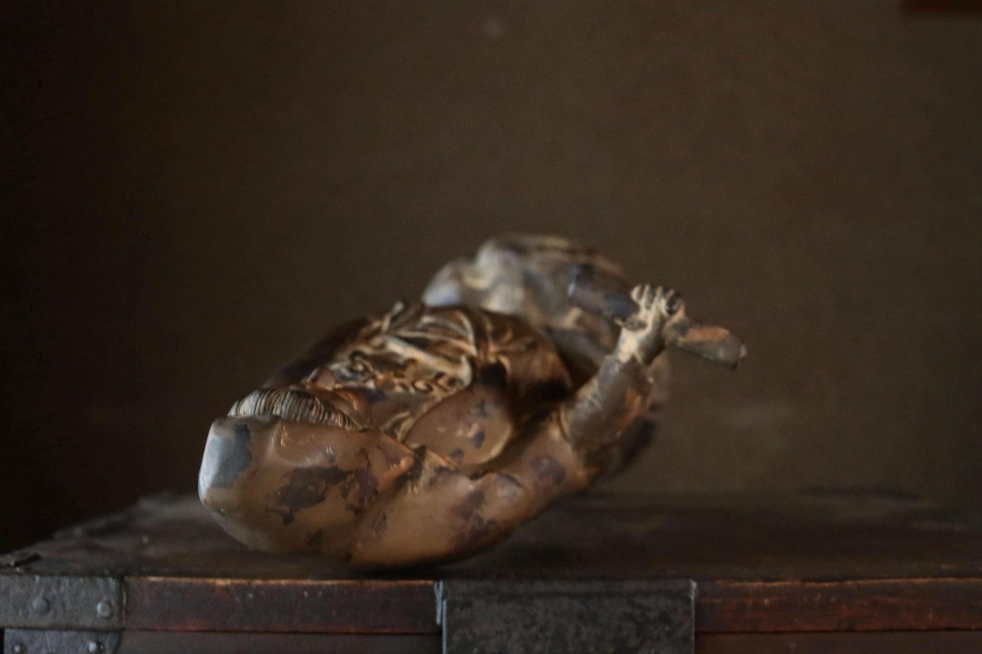A bronze statue of a person with a raised hand is displayed on a wooden surface.