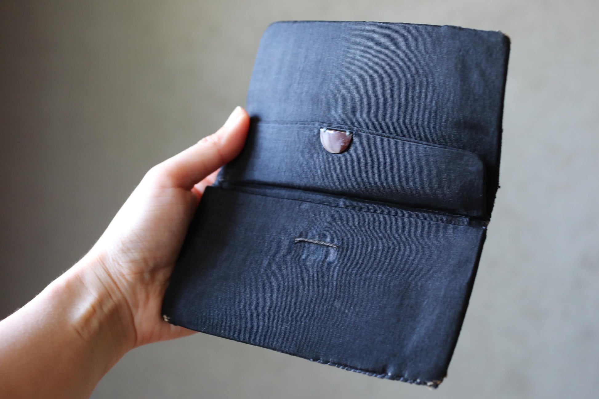 A hand holding a black wallet or purse.