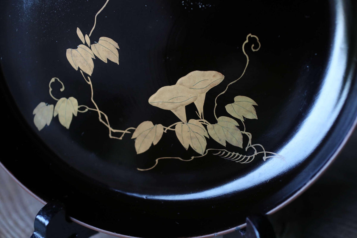 a black plate with a gold design depicting a floral pattern.