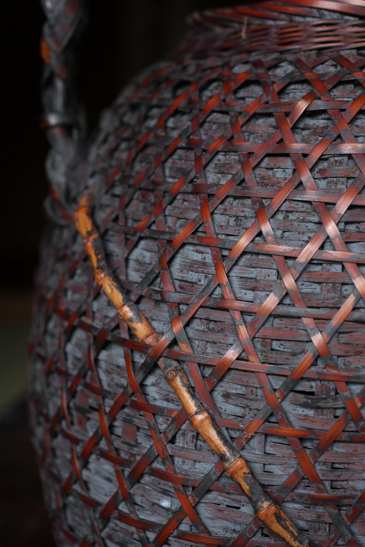 A close-up view of a woven basket with a reddish-brown color and a pattern of interwoven bamboo or straw elements.