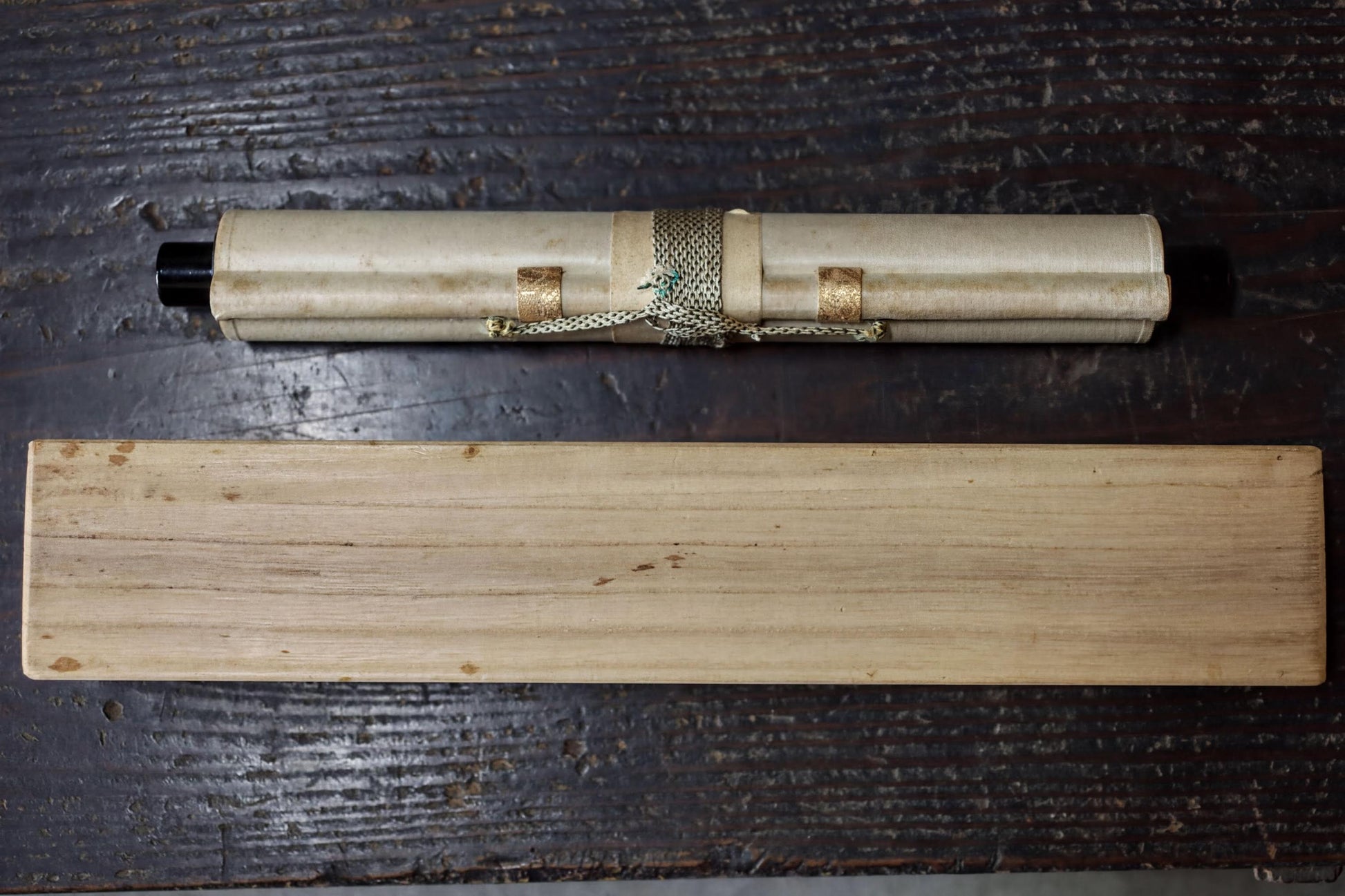 a rolled scroll and a wooden plank on a wooden surface.