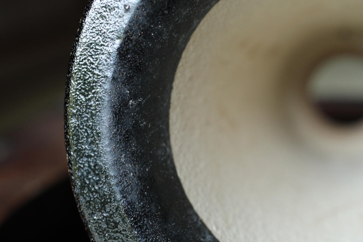 A close-up view of a black and white ceramic object, possibly a vase or bowl, with a textured surface.