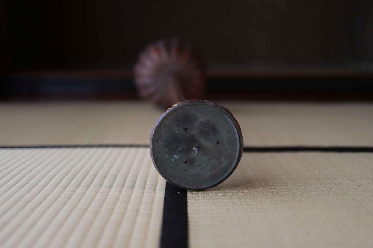 a close-up view of a dark-colored metal object, possibly a piece of furniture or a decorative item, resting on a white and black patterned surface.