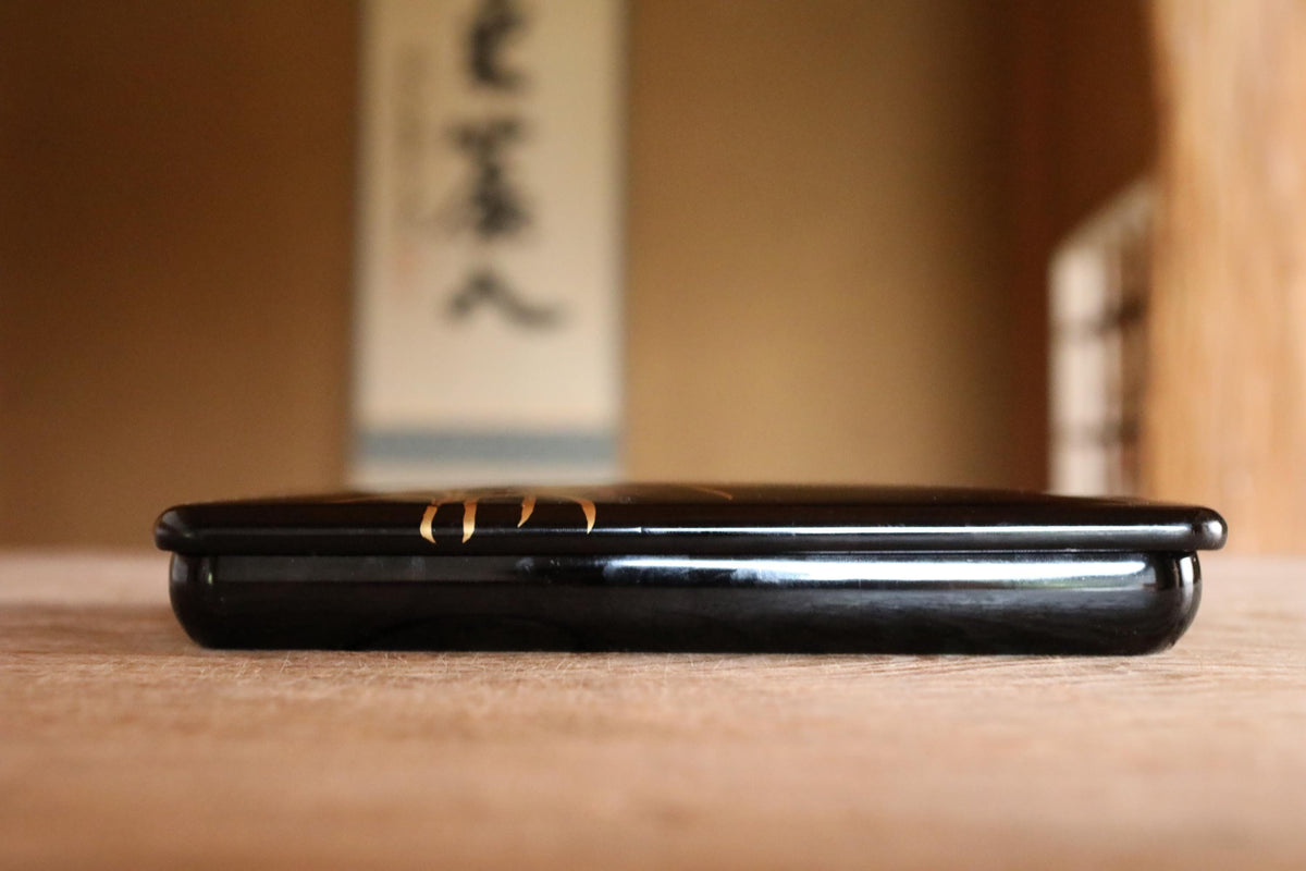 A black electronic device, possibly a laptop or tablet, is sitting on a wooden surface.
