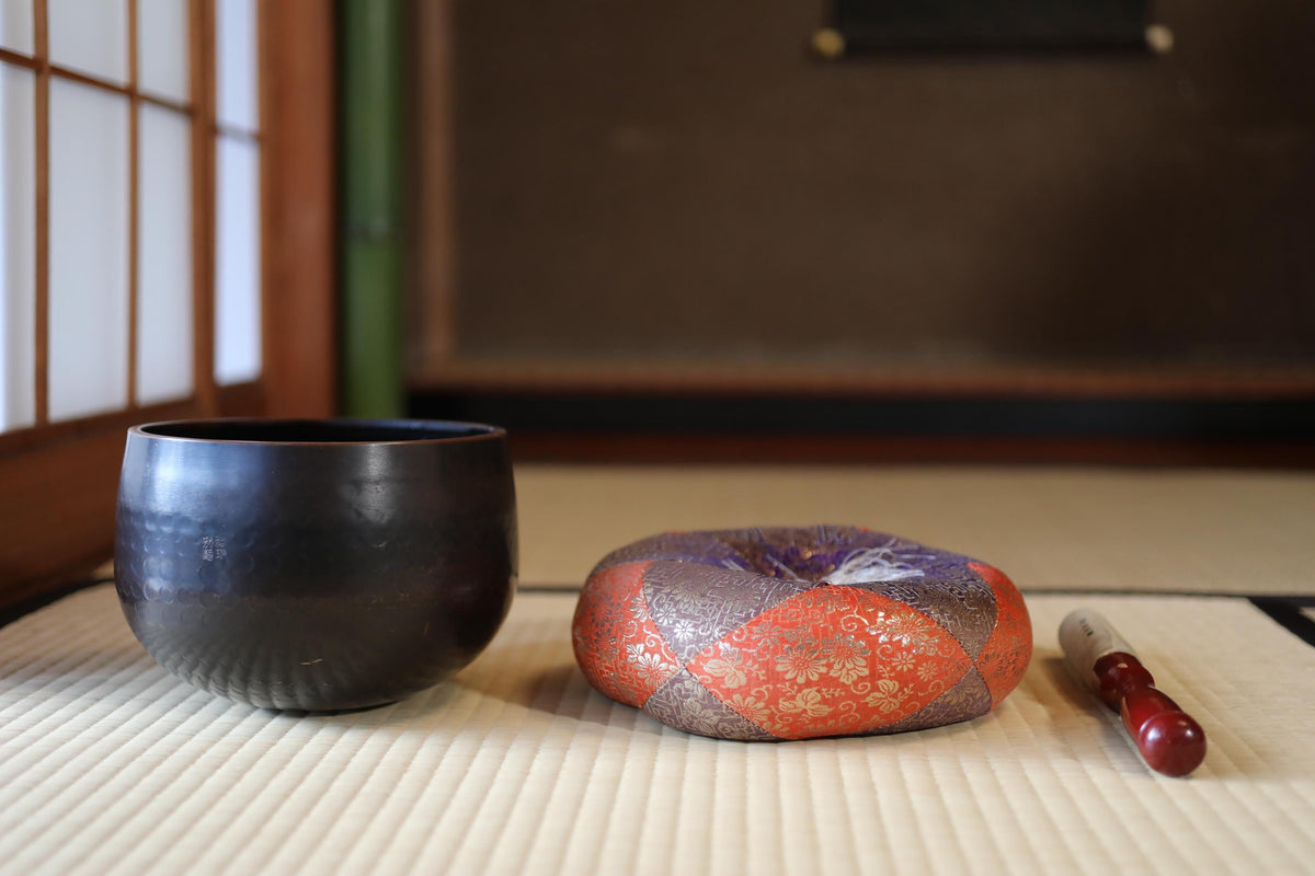 a black bowl and a red and orange decorative item placed on a white mat, with a red and white object next to them.