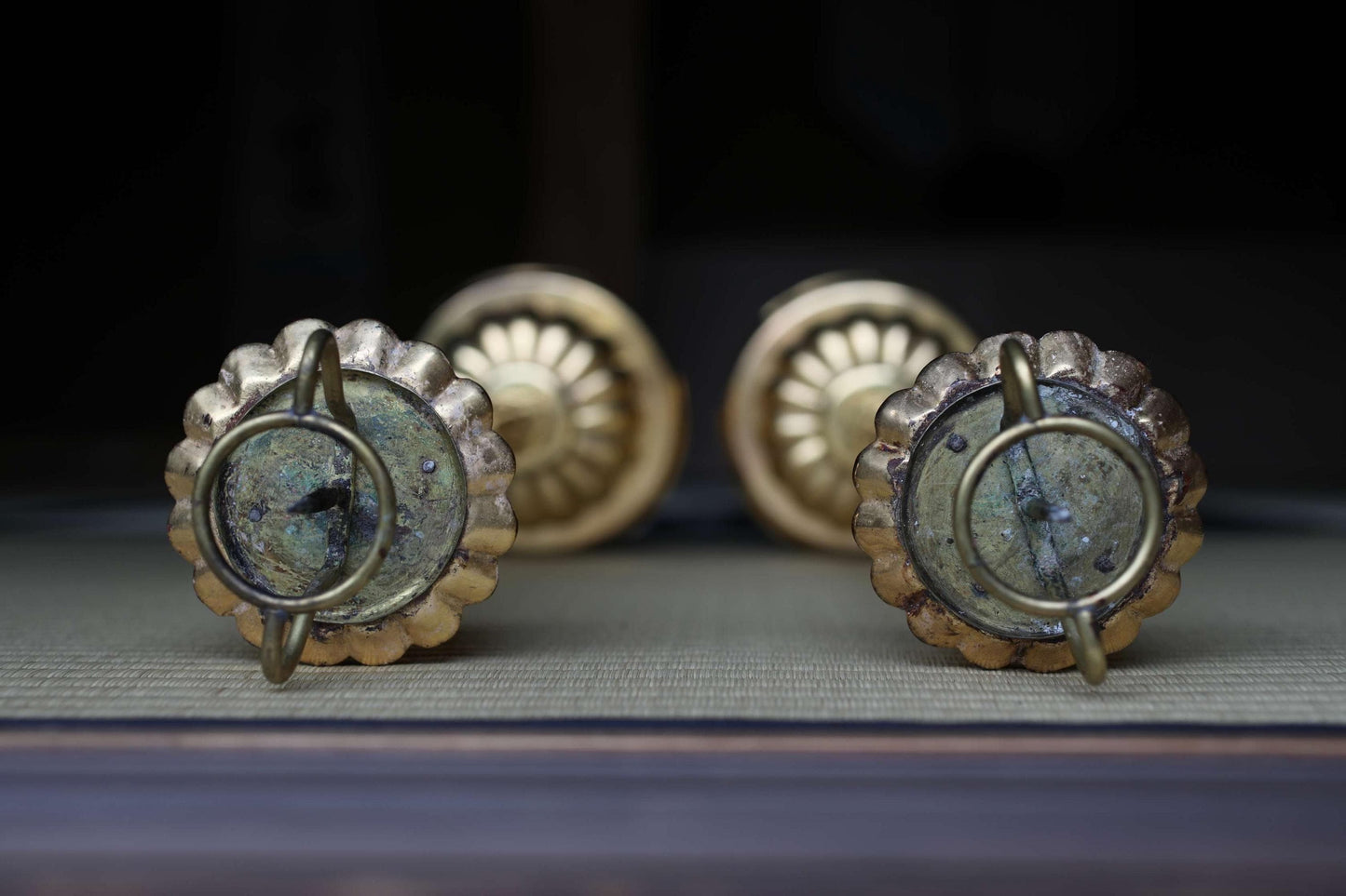 a pair of ornate brass candle holders with intricate designs, placed on a dark surface.