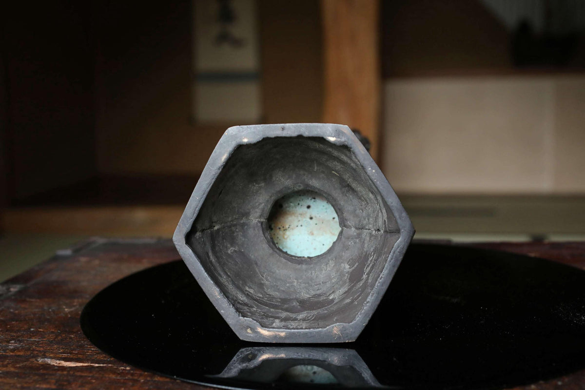 a black, hexagonal object with a blue center hole, sitting on a black surface.