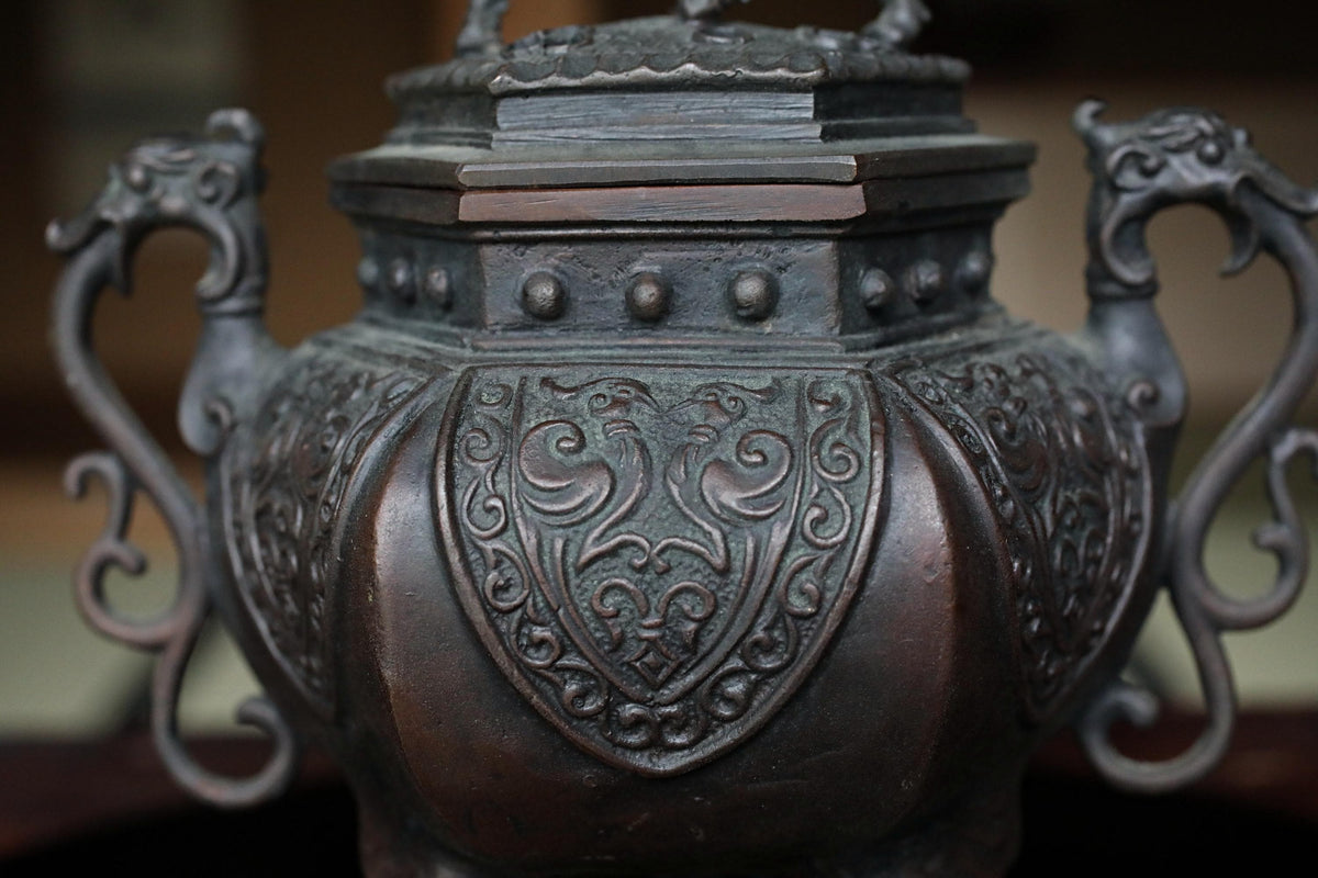 A close-up image of an ornate, antique-looking metal vase or urn with intricate designs and patterns.