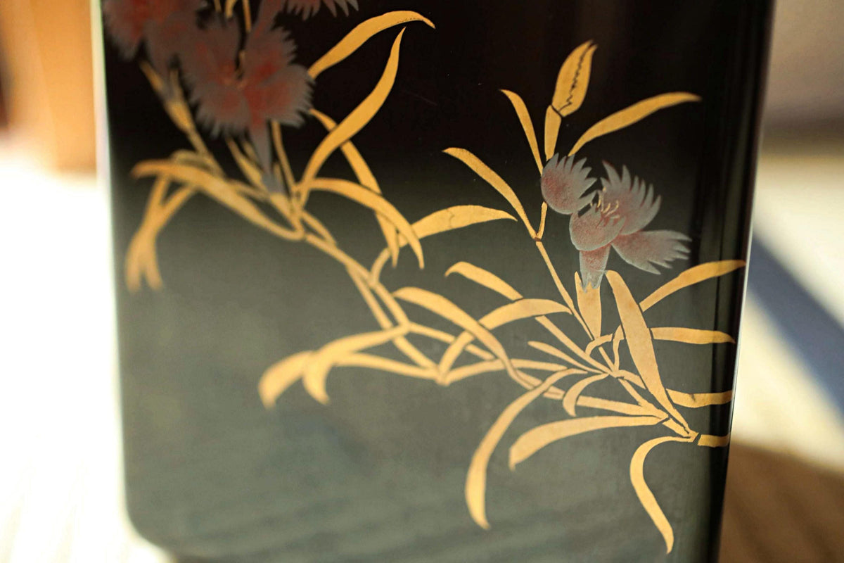a close-up view of a black vase with a floral design on it.