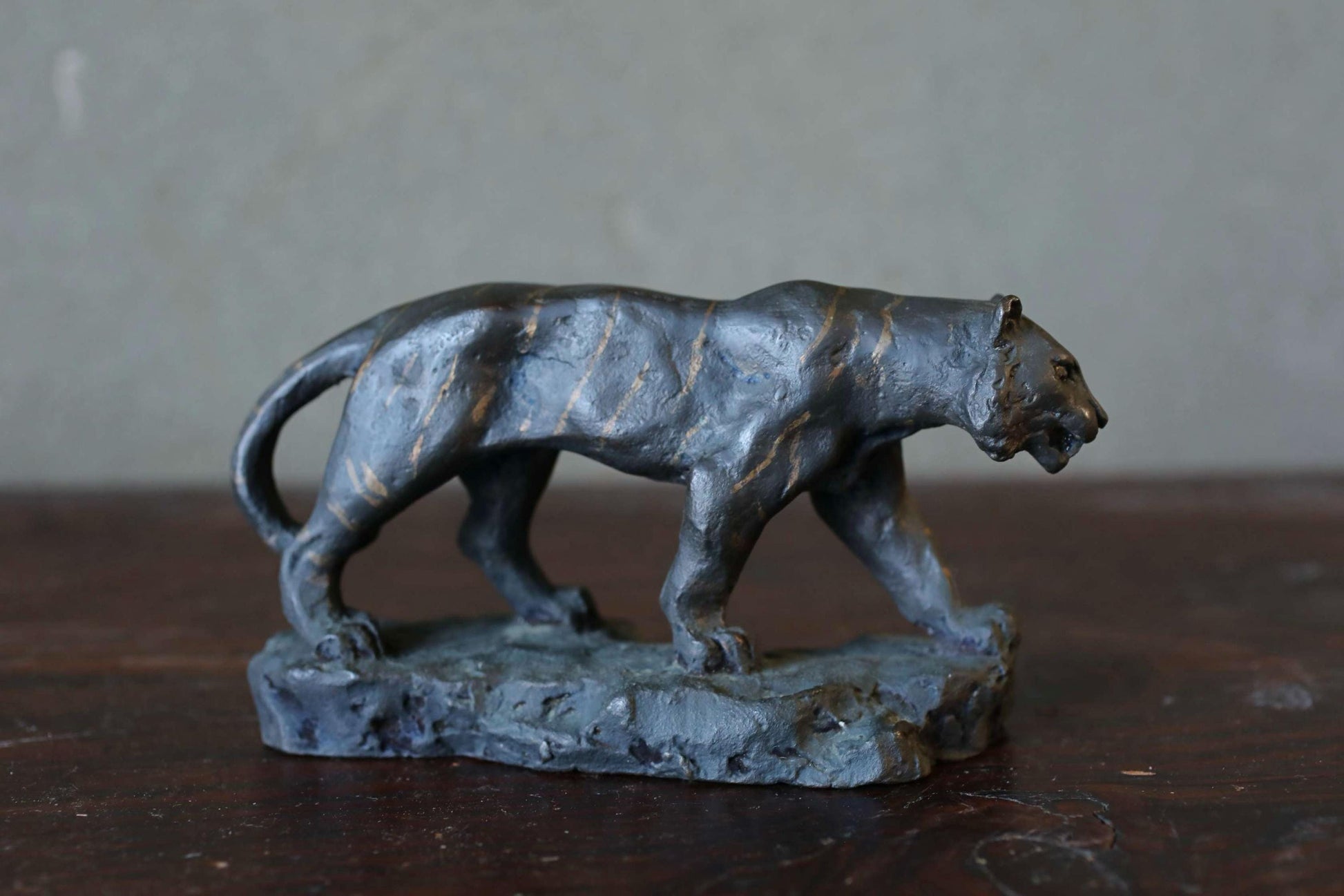 A bronze sculpture of a panther is displayed on a wooden surface.