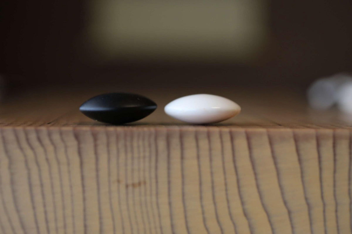 Two black and white pills are placed on a wooden surface.