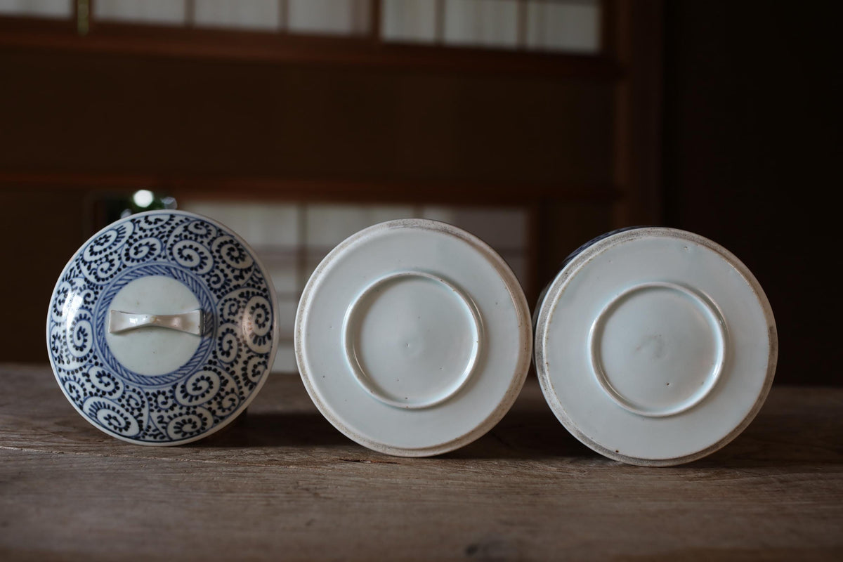 Three white ceramic plates with blue and white floral patterns are arranged on a wooden surface.