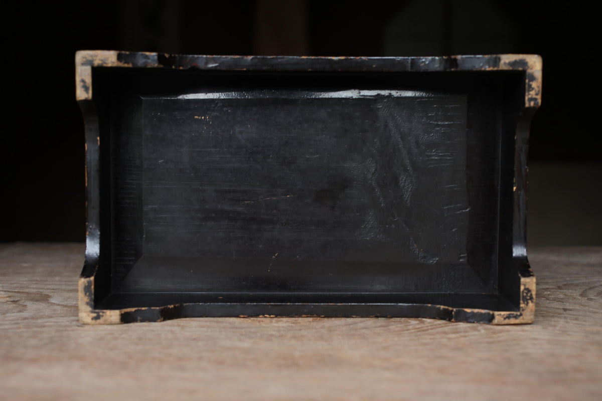 A black rectangular object with a textured surface, sitting on a wooden surface.