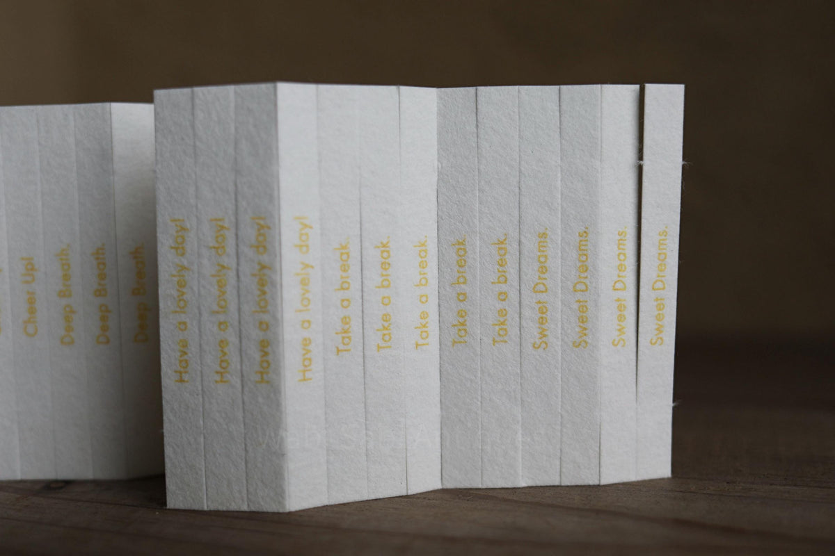 A row of white books with yellow text on their spines, arranged on a wooden surface.