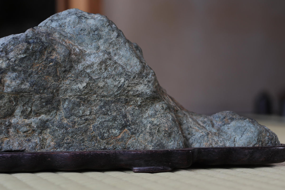 A large, gray rock sits on a dark wooden base, creating a striking contrast.