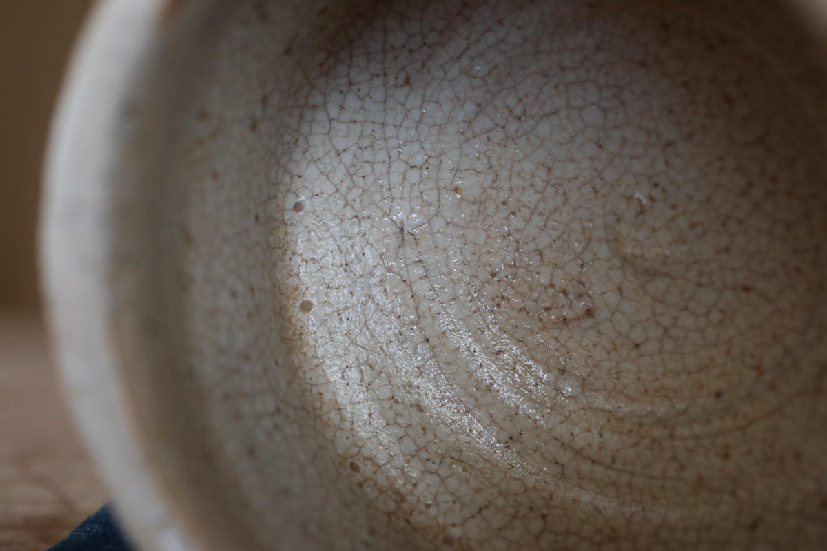 A close-up view of a white ceramic mug with a textured, cracked surface.
