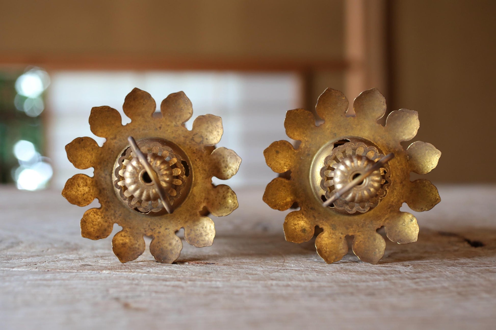 Two ornate brass candle holders with intricate floral designs, placed side by side on a wooden surface.