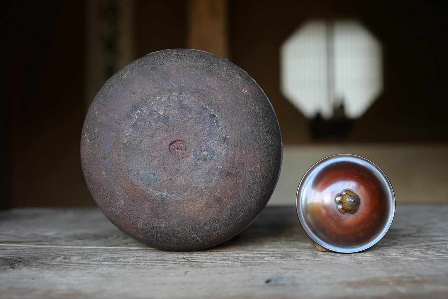 a large, rusted metal bowl and a smaller, shiny metal bowl placed on a wooden surface.
