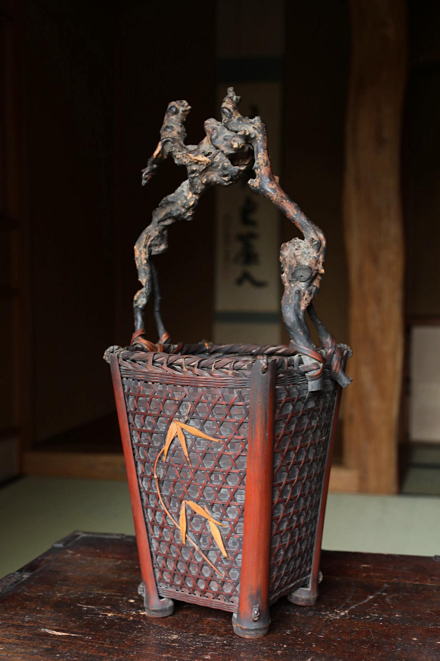 An antique metal basket with a woven design, placed on a wooden surface.