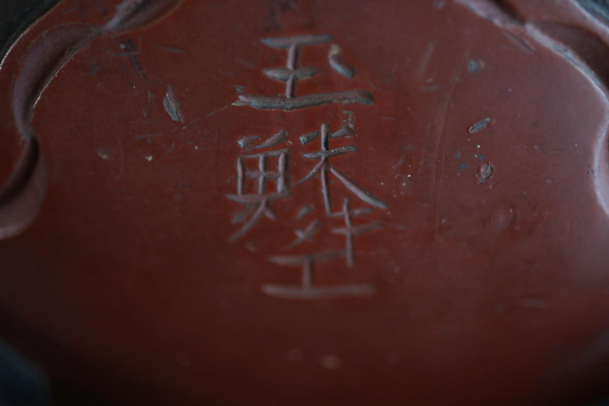 a close-up view of a dark red surface with a carved inscription in a foreign language.