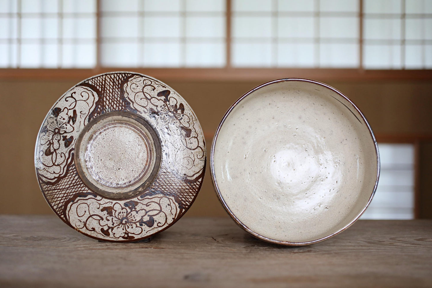 Two ceramic bowls, one with a floral design and the other plain white, are placed side by side on a wooden surface.