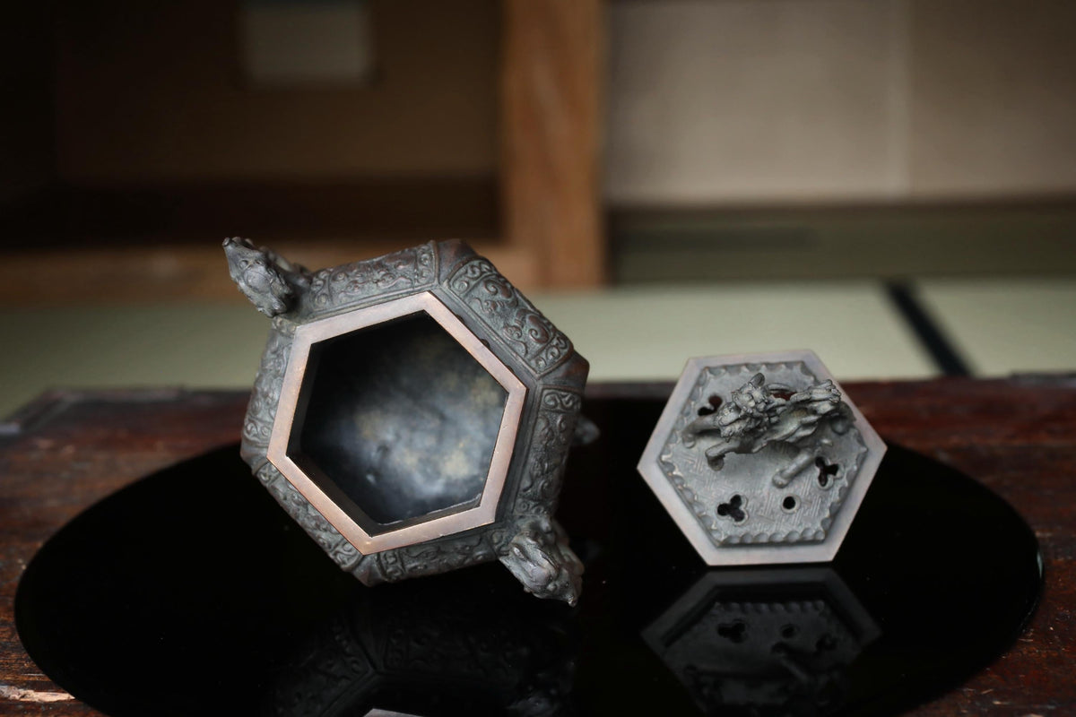 a decorative metal object with an intricate design, placed on a reflective surface.