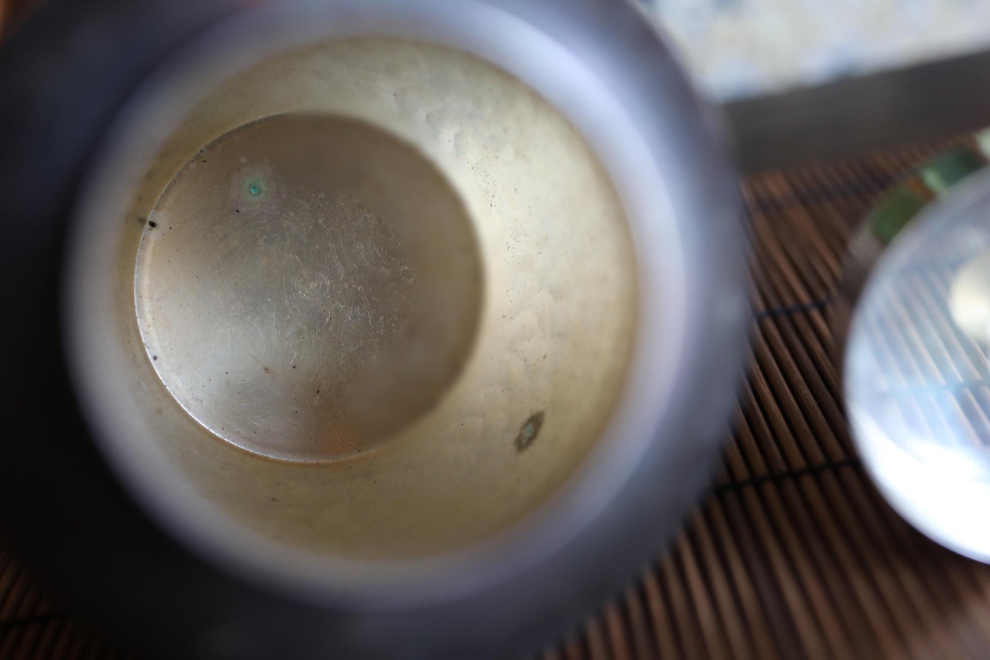 the inside of a silver teapot, with a blurred background that appears to be a wooden surface.