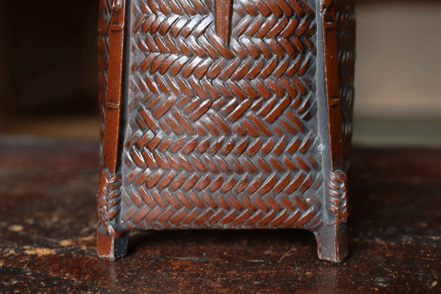 A close-up view of a wooden object with a woven pattern, possibly a piece of furniture or a decorative item.