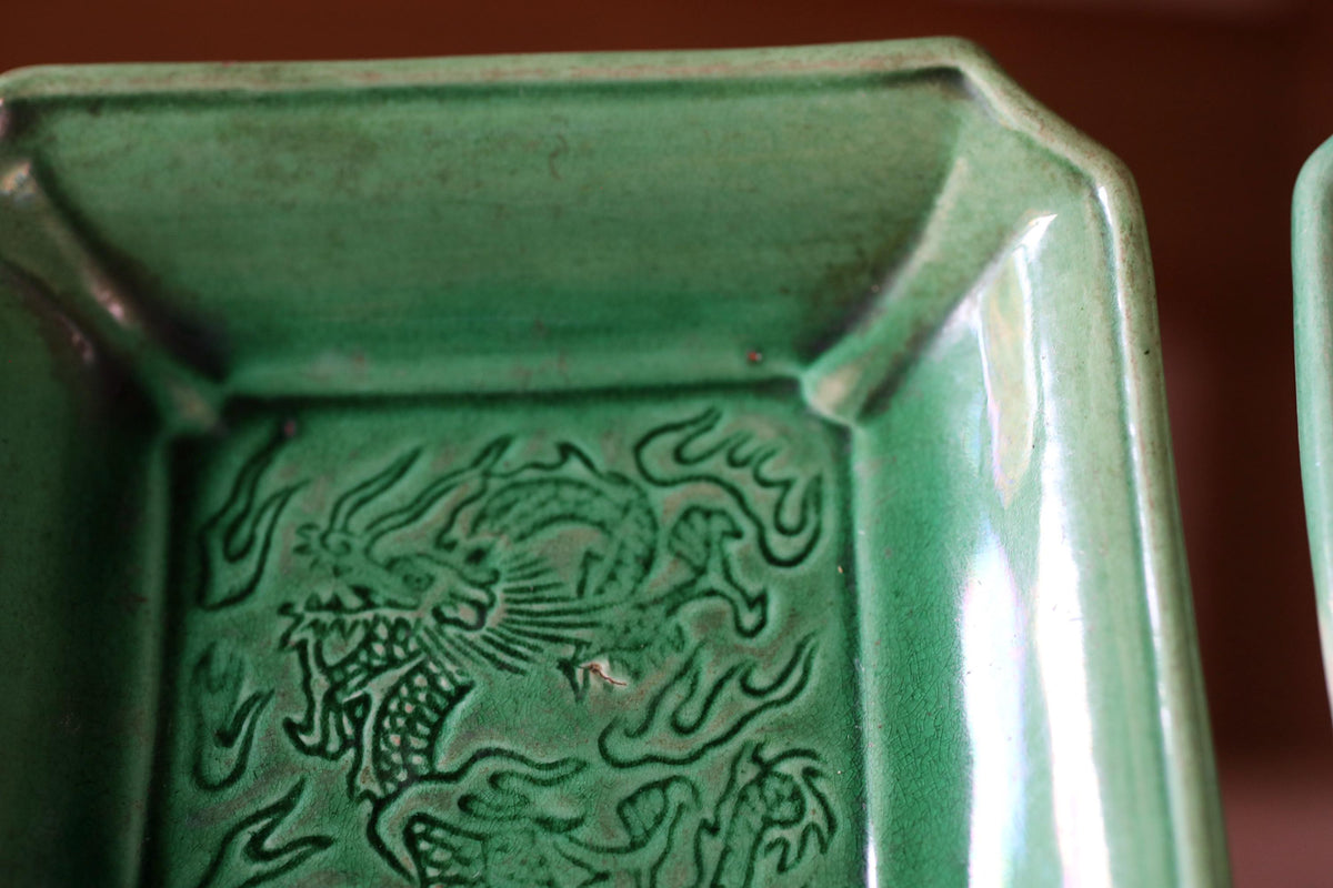 A close-up view of a green ceramic dish with an intricate dragon design on it.