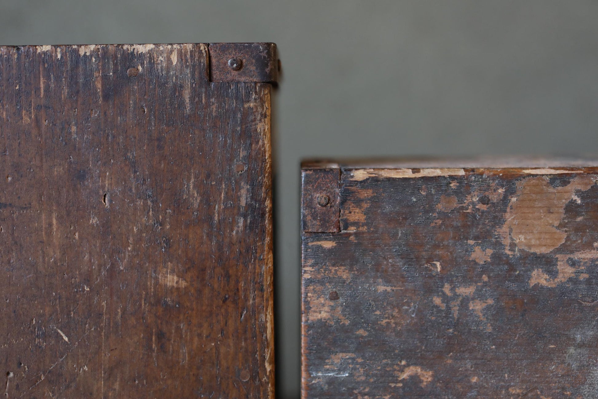 two old, weathered wooden boxes with peeling paint and visible signs of wear, suggesting they have been exposed to the elements for an extended period of time.