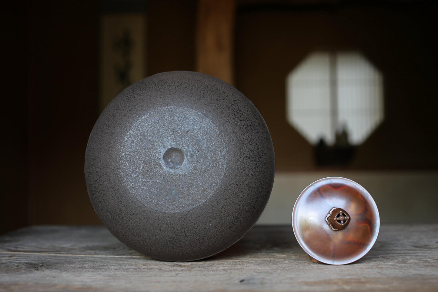 a large, round, dark grey ceramic bowl and a smaller, round, brown ceramic bowl placed on a wooden surface.