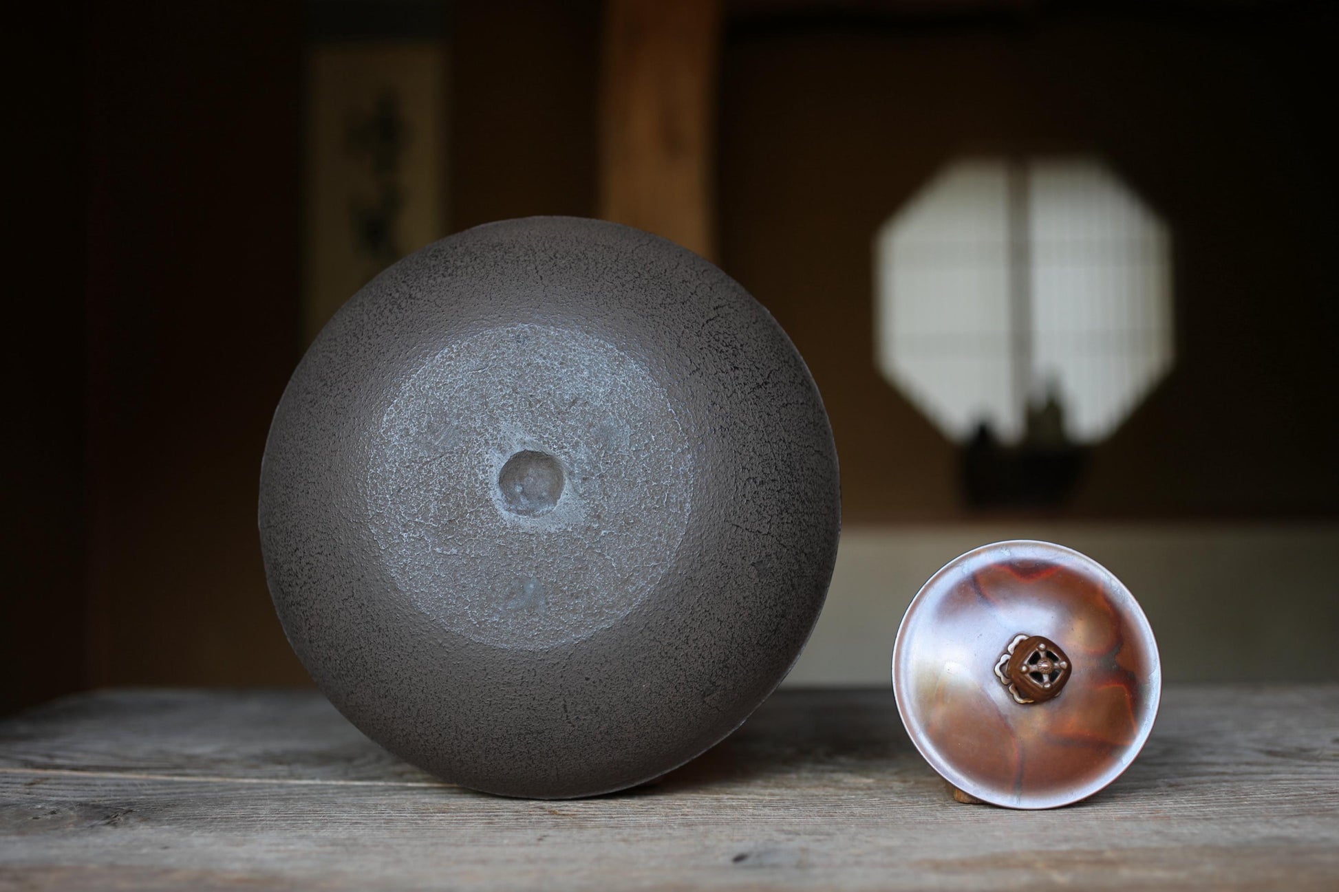 a large, round, dark grey ceramic bowl and a smaller, round, brown ceramic bowl placed on a wooden surface.